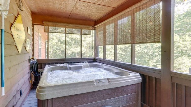 Ein Whirlpool in einer Holzhütte mit großen Fenstern und einem Schild mit der Aufschrift 'Danger Curvy'.