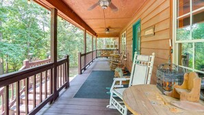 Eine überdachte Veranda mit Holzbalkonen, Deckenventilator und einer Reihe von Holztischen und -stühlen.