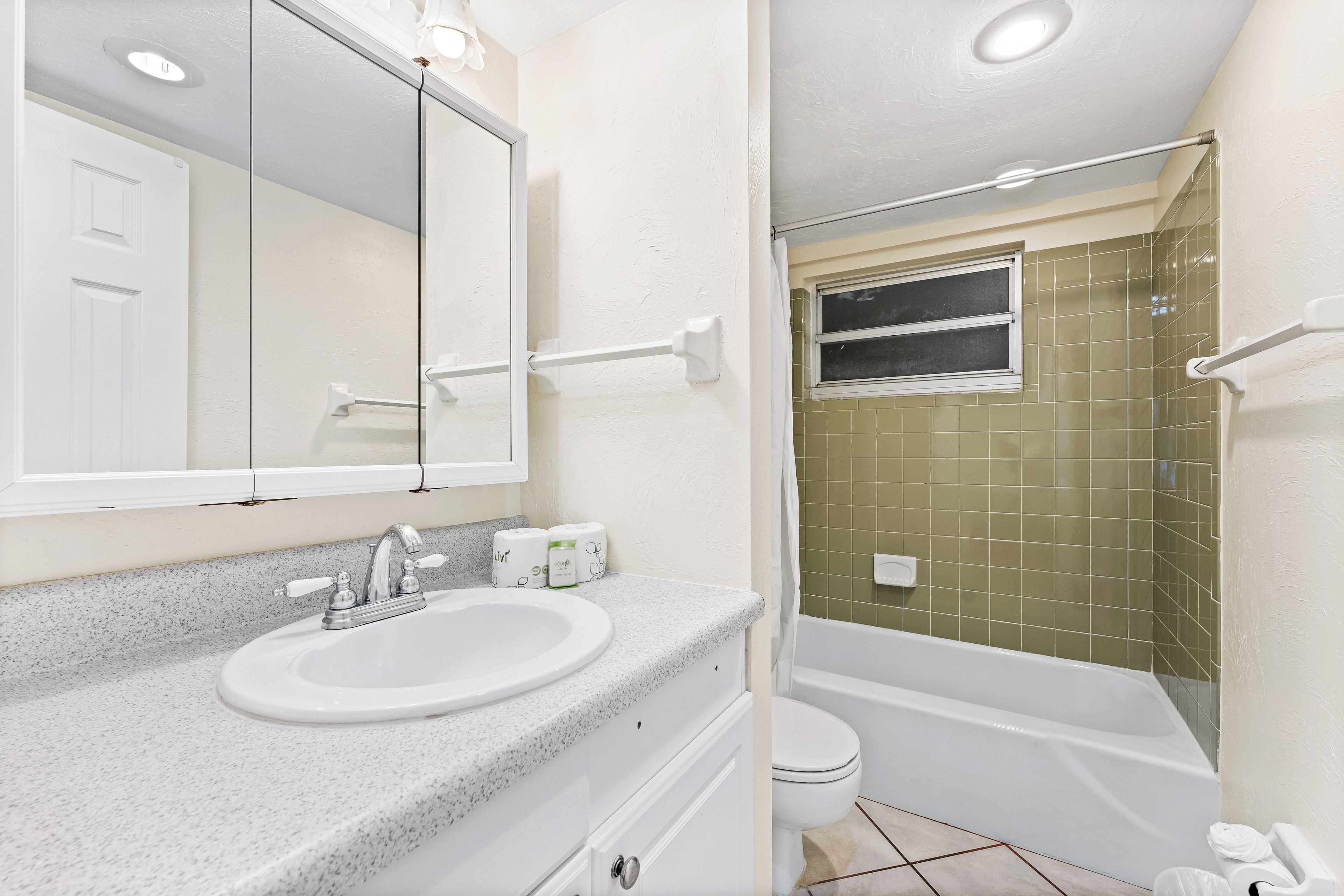 Un baño con lavamanos, espejo y bañera blancos.