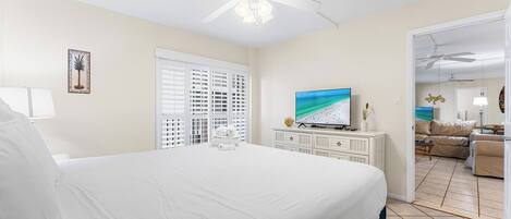 Une chambre d’hôtel avec un grand lit, un ventilateur de plafond, une télévision et une vue sur l’espace de vie.