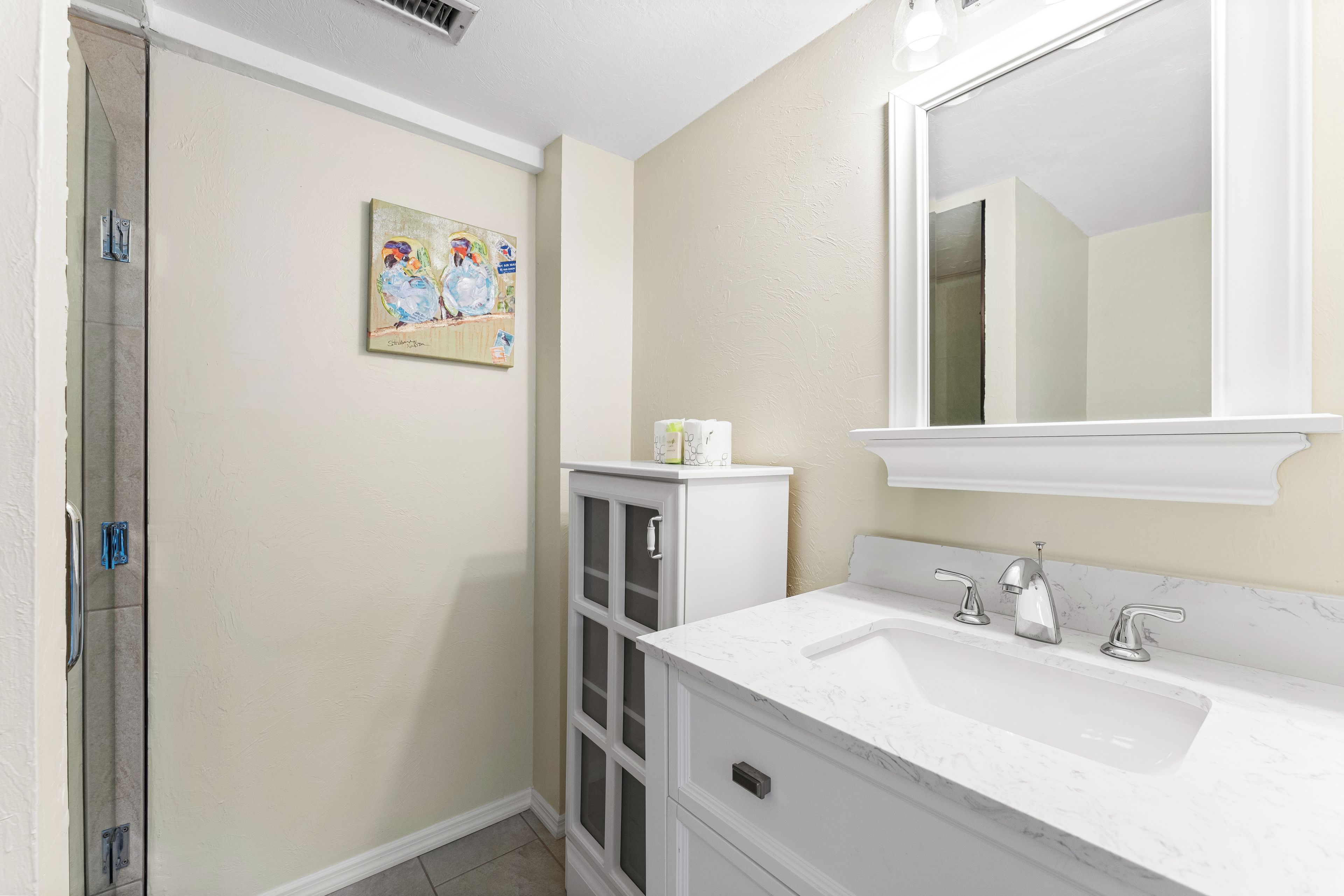 A bathroom with a white sink, a large mirror, and a shower.