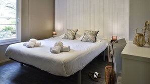 A neatly made bed with white linens and towels, a bedside lamp, and a small table with a lamp and decorative items. - Propriano Chalet near Sandy Beaches (Propriano)