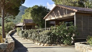 A pathway leading to a building with a tiled roof, surrounded by stone walls and greenery. - Propriano Chalet near Sandy Beaches (Propriano)