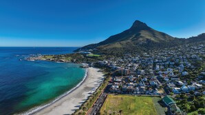 An aerial view of a coastal town with a prominent mountain, a beach, and residential areas. - 26OnFirst: UPS, Sea Views & Personalised Service (Cape Town)