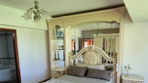 Quarto com cama grande, lustre, espelho e piso em azulejos.