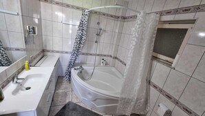 Casa de banho com banheira, lavatório e chuveiro.