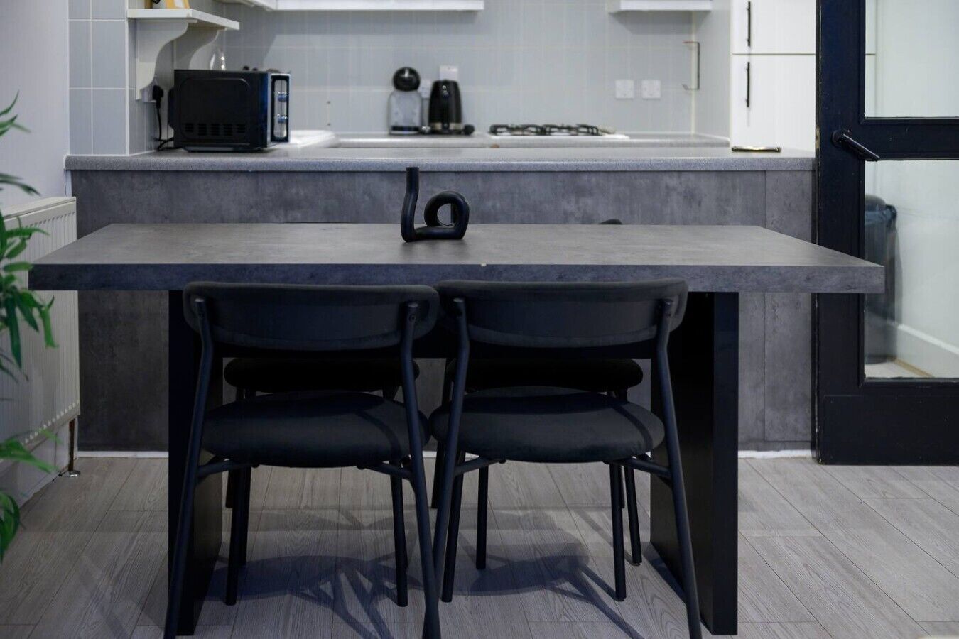 A modern kitchen with a dark countertop, two black chairs, and a black appliance.