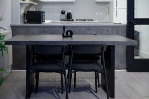 A modern kitchen with a dark countertop, two black chairs, and a black appliance.