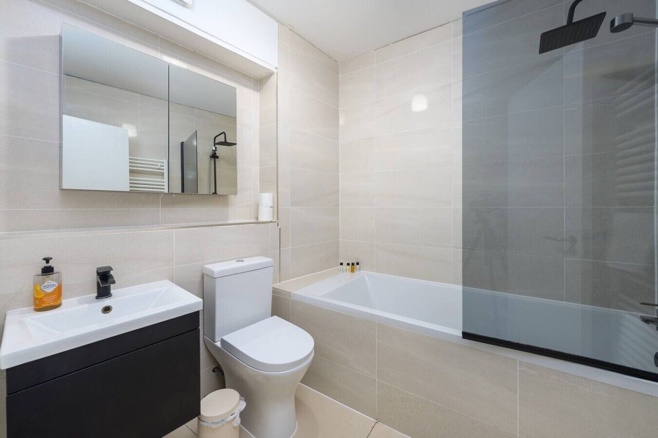 A modern bathroom with a white sink, toilet, and bathtub.