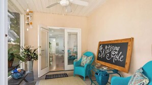 Une pièce chaleureuse avec des fauteuils de couleur turquoise, une enseigne en bois sur laquelle on peut lire « The Watering Hole », et un ventilateur de plafond.