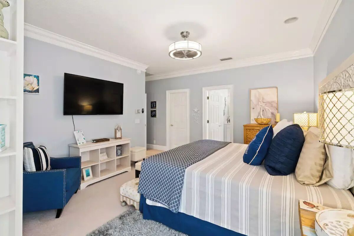 Ein Schlafzimmer mit Bett, Fernseher, Schreibtisch und Stuhl.