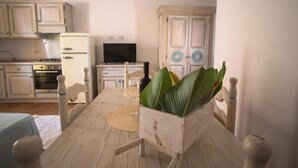 A dining table with chairs, a television, and a kitchen in the background. - Superb Le Residenze del Golfo di Orosei No2186h (Orosei)
