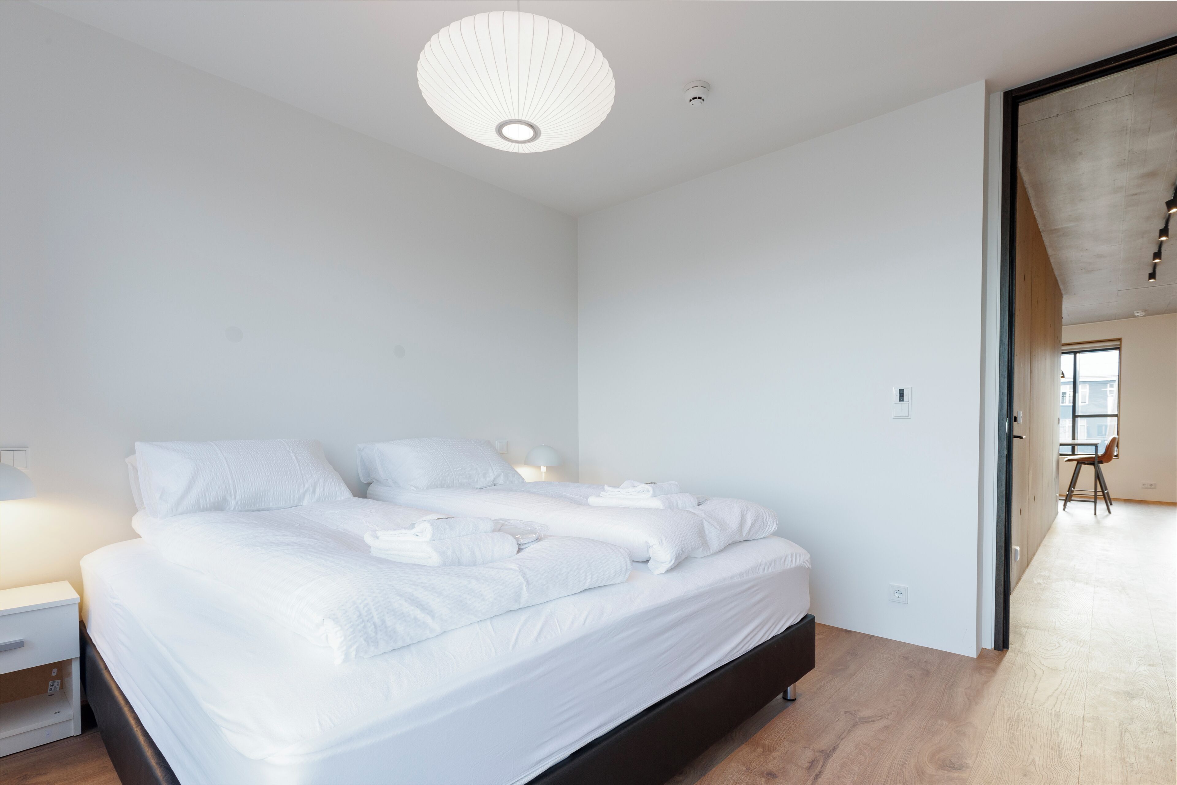 A modern bedroom with a large bed, a bedside table, and a ceiling light fixture.