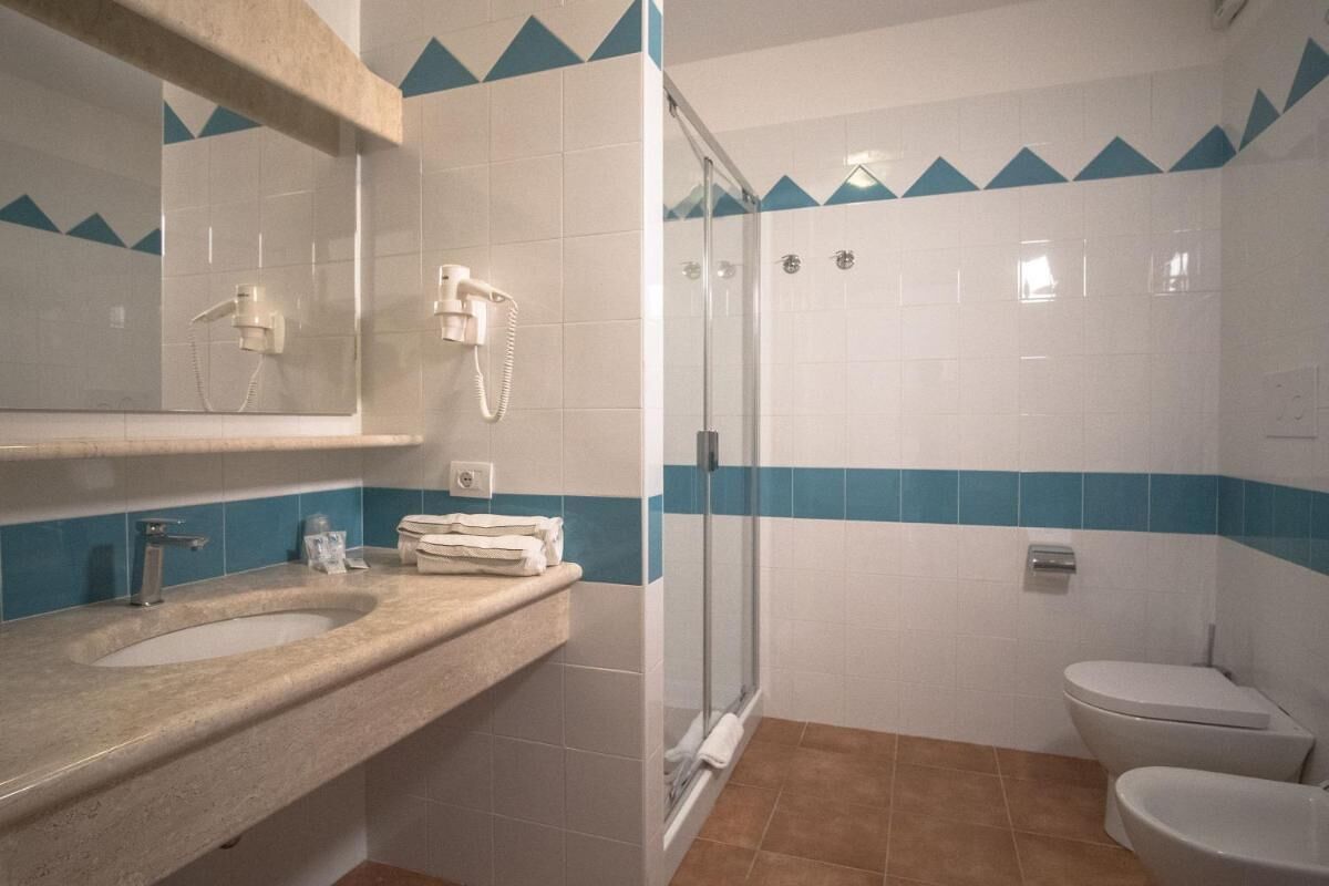 Un bagno con doccia, due lavandini e un water.