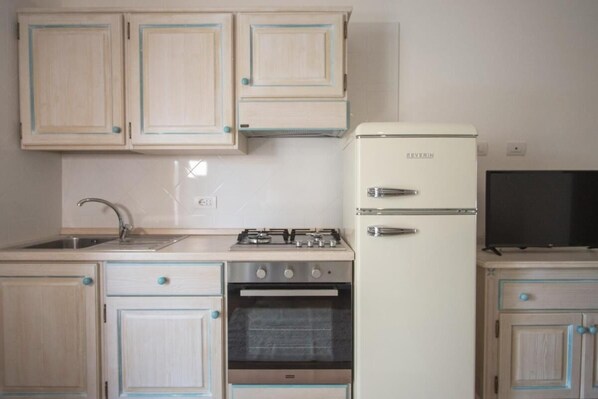 Une cuisine équipée d’une cuisinière, d’un four, d’un réfrigérateur et de placards.