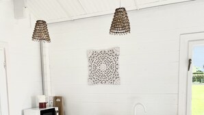 A compact kitchen with a microwave, sink, and two pendant lights.