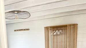 A bedroom with a bed, a wooden wardrobe, a hanging light fixture, and a rug.