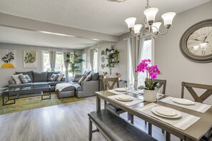 Un salon moderne comprenant un ensemble de canapés, une table à manger et un lustre.