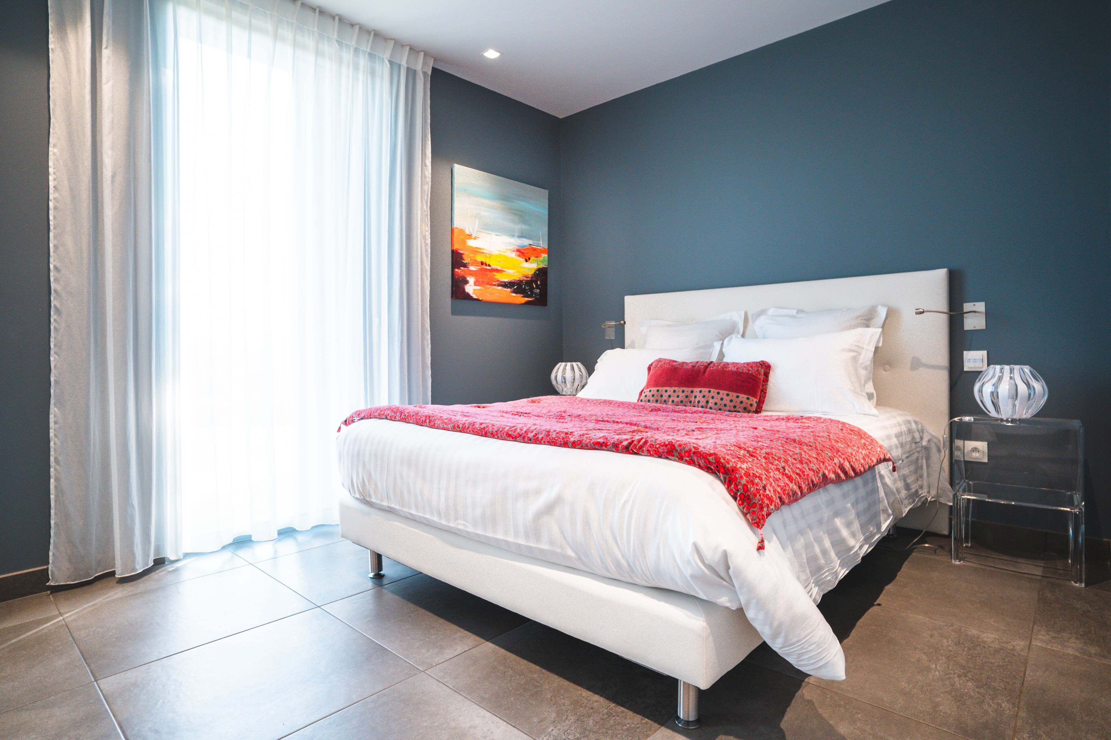 Une chambre à coucher moderne avec un grand lit, une table de chevet et un tableau au mur.