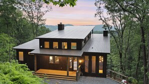 Une maison moderne à deux étages, avec une façade en bois, de grandes fenêtres et une terrasse.