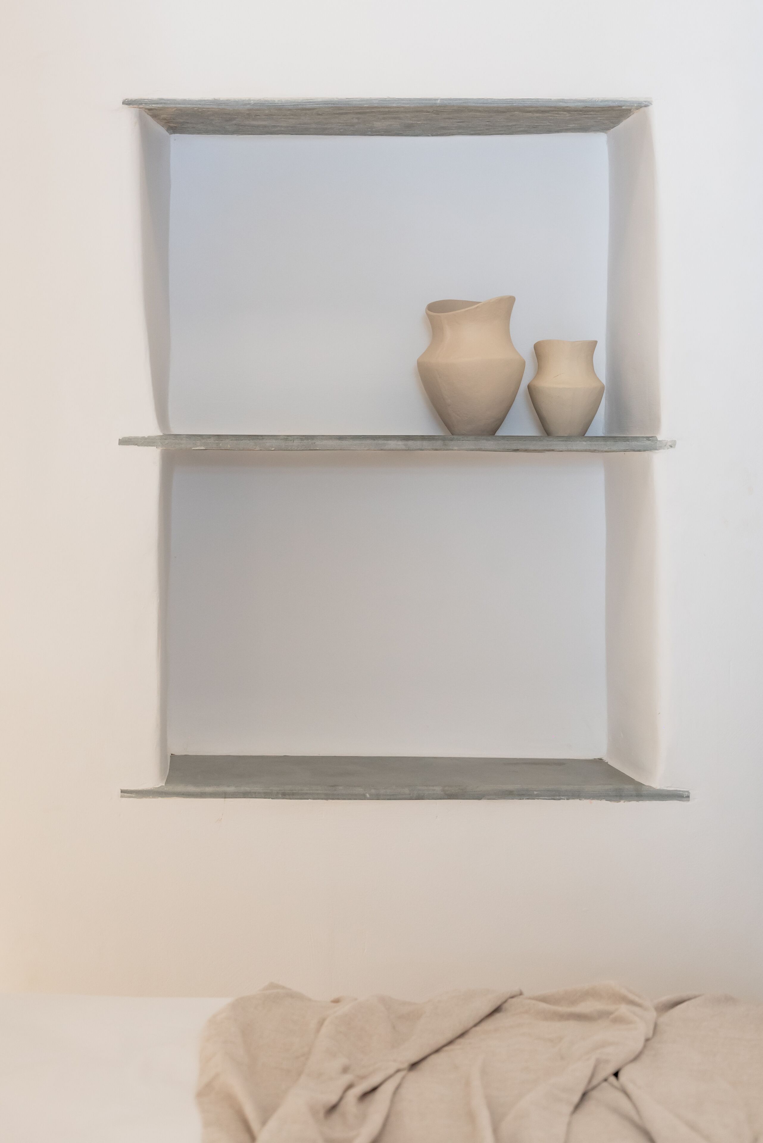 A wall-mounted shelf with two ceramic vases.