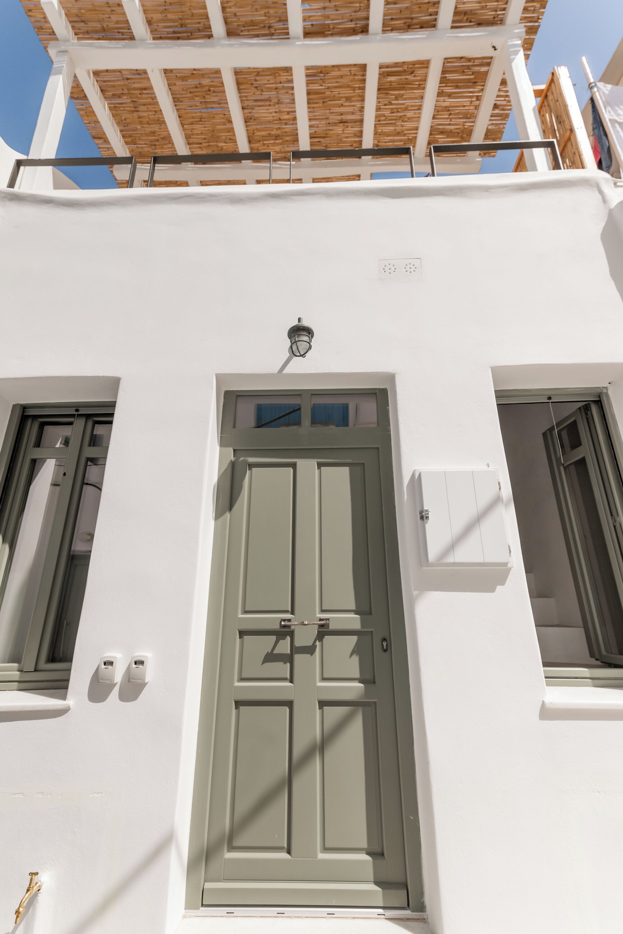 Un bâtiment blanc avec une porte verte, deux fenêtres et une structure de plafond en bois.