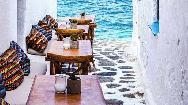 Un pequeño espacio al aire libre con mesas y sillas, que ofrece vistas al mar.