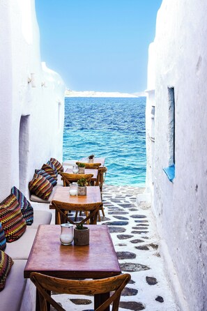 Un petit espace extérieur aménagé avec des tables et des chaises, qui offre une vue sur la mer.