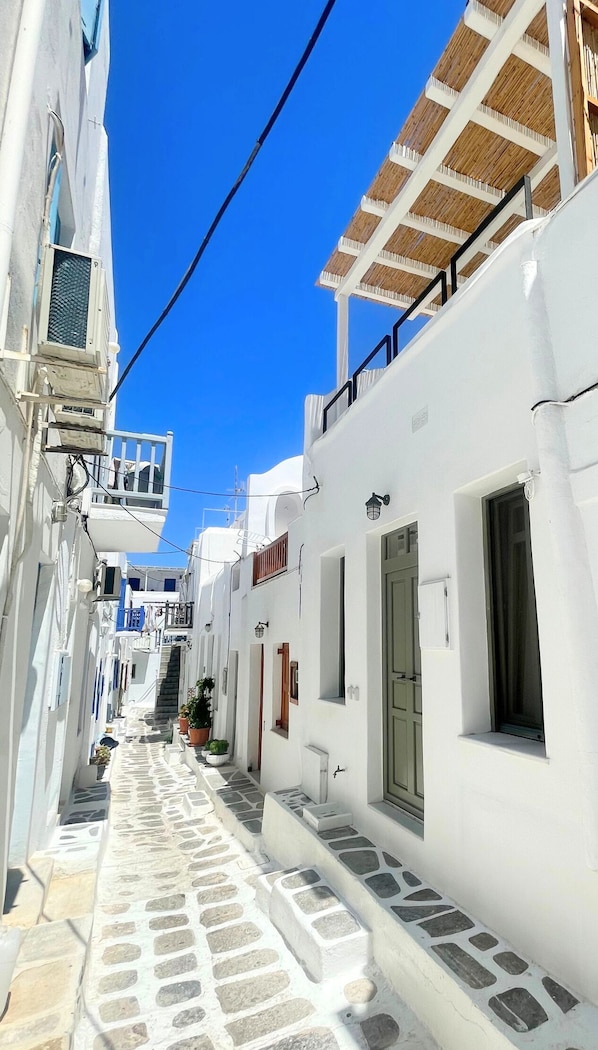 Une rue étroite bordée de bâtiments blancs, d’escaliers en pierre et d’un ciel d’un bleu limpide.