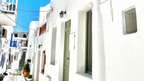 Una calle estrecha con edificios blancos, un camino adoquinado de piedra y un cielo azul despejado.