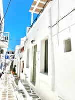 Una calle estrecha con edificios blancos, un camino adoquinado de piedra y un cielo azul despejado.