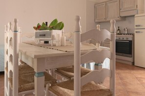 Une table à manger avec des chaises, une petite plante et un meuble blanc en arrière-plan.
