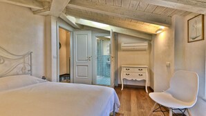 Un dormitorio con cama, una silla, cómoda y aire acondicionado.