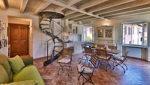 Un espacio habitable amplio con una escalera en espiral, una mesa de comedor con sillas y una zona de estar acogedora con un sofá verde.