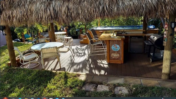 An outdoor bar area with a thatched roof, wooden deck, and a pool table. - Introducing our new Waterfront Hideaway Studio  (Palm City)