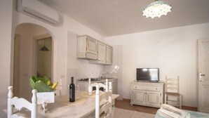 A compact kitchen with a dining table, chairs, a television, and cabinets.