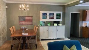 A dining area with a wooden table and chairs, a white cabinet with glass doors, and an American flag on the wall. - Heroes Boulevard House with room for up to ten (Lawton)