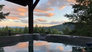 A hot tub with a clear view of the surrounding landscape, including trees and distant hills. - Big Mountain Treehouse!  Beautiful cabin home w/ SPECTACULAR views of Lake (Whitefish)