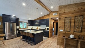 A modern kitchen with a central island, dark cabinetry, and wooden accents. - Cabin with hot tub, heated swimming pool and acres of backyard hiking  (Adams)