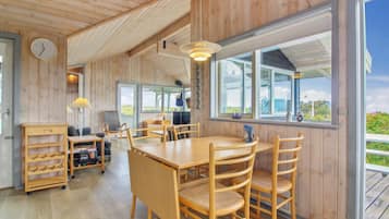 Un intérieur en bois comprenant un coin repas, une horloge et de grandes fenêtres.