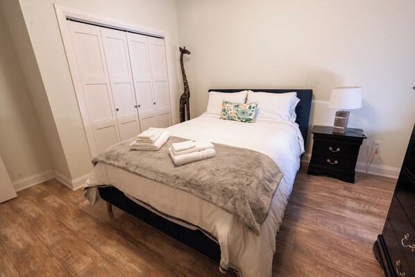 Une chambre à coucher comprenant un lit, une table de chevet, une commode, une armoire et un objet décoratif en forme de girafe.