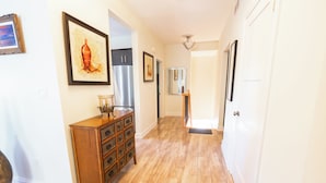 Un couloir avec un plancher en bois, une commode en bois et un réfrigérateur.