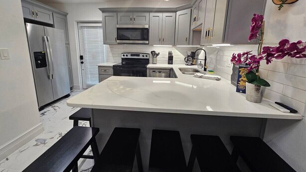 A modern kitchen with a central island, stainless steel appliances, and pendant lighting.
