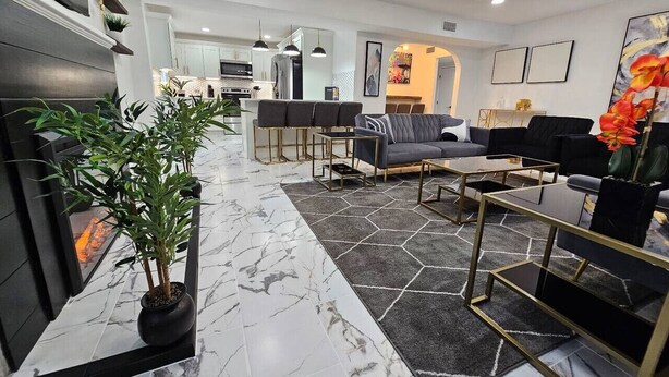 Una sala de estar moderna con piso de mármol, un conjunto de sofá, una mesita de centro y una planta en maceta.