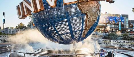 Un globo grande con la palabra "UNIVERSAL" sobre él, rodeado por una fuente.