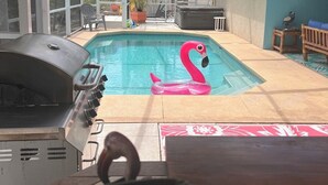 Ett takförsett utomhusområde med en pool, en grill och en uppblåsbar flamingofigur.