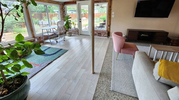 Un amplio salón con un gran ventanal, un sofá, un televisor y una mesa de comedor.