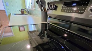 Una cocina con una placa de inducción negra y un horno de acero inoxidable.