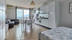 A modern apartment with a dining area, kitchen, and a bed. - Lydie apt. exclusive holigarda (Desenzano del Garda)