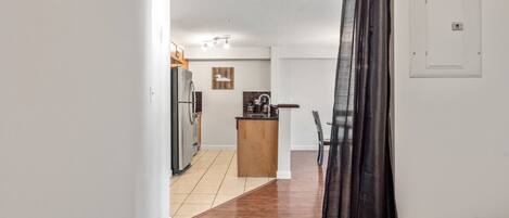 Una cocina compacta con electrodomésticos modernos, una pequeña isla y un comedor con una silla.